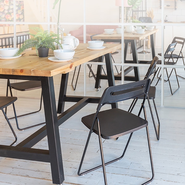 Mobiliario para restaurante con mesa de madera clara y sillas negras, estilo de muebles minimalistas ideal para comedores corporativos